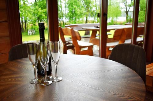 a table with a bottle of wine and two wine glasses at Kaimukas - namelis prie ežero keturiems in Dvarčėnai