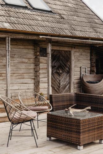 a patio with two chairs and a table and a building at Vienkiemio Oazė - Namelis Prie Upelio in Galvokai