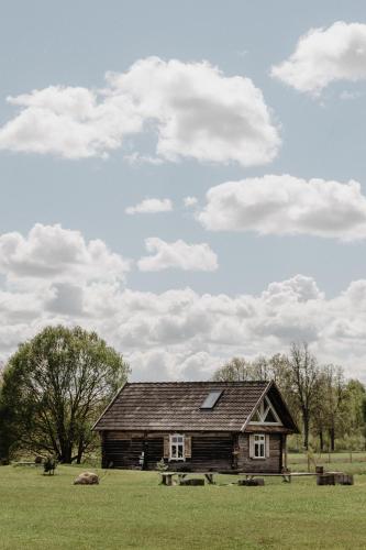 an old house in a field with a sky at Vienkiemio Oazė - Namelis Prie Upelio in Galvokai