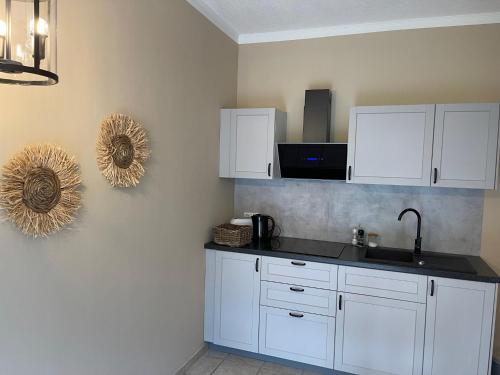 a kitchen with white cabinets and a sink at Naturnahes, neu eingerichtetes Apartment mit 1 Schlafzimmer in Neu Gaarz
