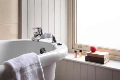 baño blanco con lavabo y ventana en The Bianconi Inn, en Killorglin