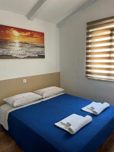 a bedroom with a blue bed with towels on it at Holiday Home Rosa in Gedići