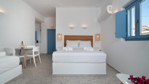 a white bedroom with a bed and a table at Camvillia Donoussa Village Suites in Donoussa
