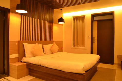 a bedroom with a bed with white sheets and pillows at Casa De Mount in Mount Ābu