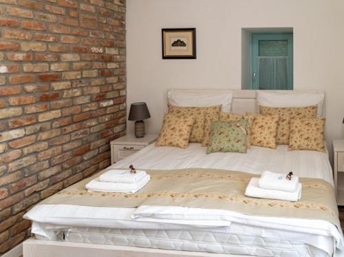 a bedroom with a white bed with a brick wall at Villa Bella in Badacsonytomaj