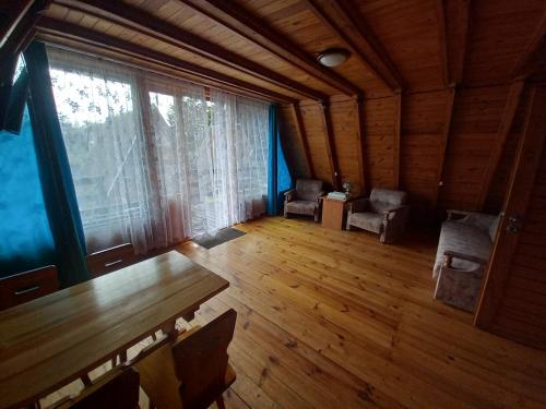 an empty room with a table and chairs and a large window at Domki Letniskowe KORMORAN in Kąty Rybackie