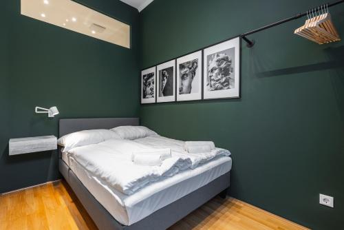 Cette chambre verte dispose d'un lit avec 4 photos sur le mur. dans l'établissement Trendy apt with - smart TV, coffee machine in Meidling, à Vienne
