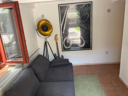 a living room with a couch and a guitar on the wall at Ádám Apartman in Balatonföldvár