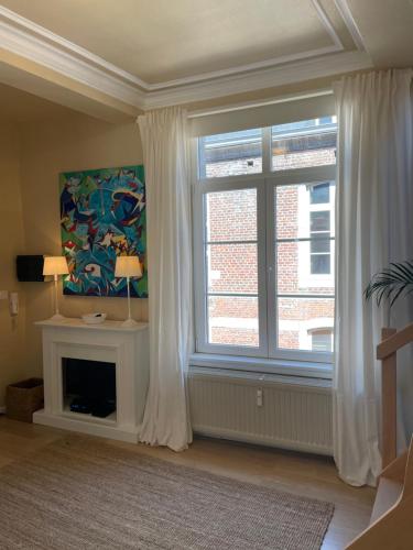 a living room with a large window and a fireplace at Le 25, Duplex élégant au cœur du piétonnier historique in Namur