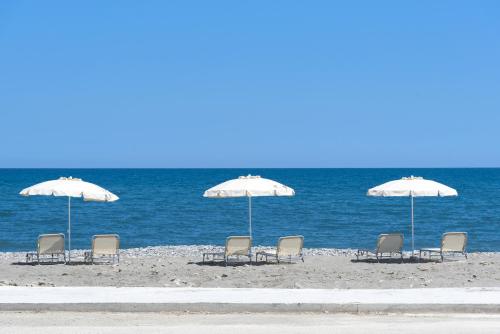un grupo de sillas y sombrillas en la playa en Amalthia Villa, an Evanescence Retreat, By ThinkVilla en Tavronitis