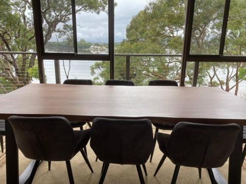 a large wooden table with chairs in front of a window at Phegans Bay Waterfront Retreat in Blackwall