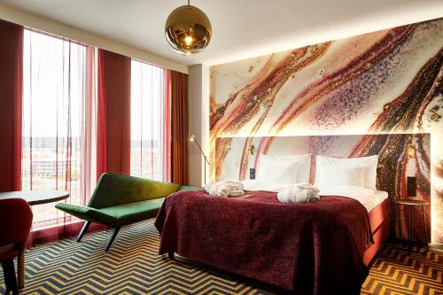 a hotel room with a bed and a green chair at ProfilHotels Halmstad Plaza in Halmstad
