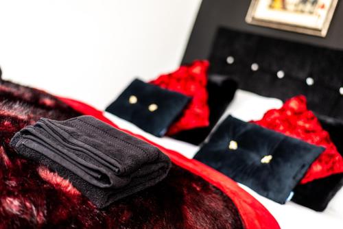 a bed with black and red pillows on it at Alice in Wonderland cottage by the sea in Torquay