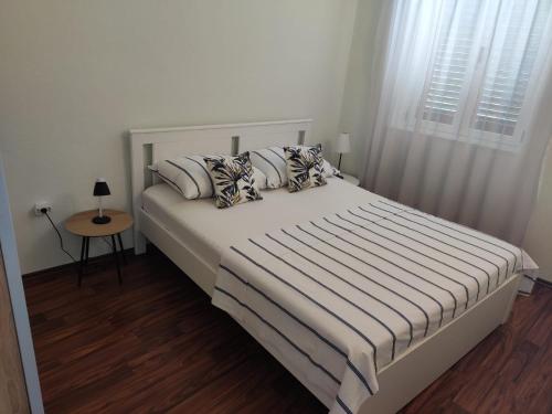 a bedroom with a white bed with pillows and a window at Apartment Dalma in Podgora