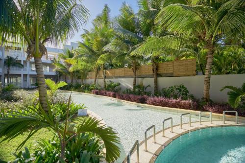 a swimming pool with palm trees in a resort at Ki Residences with LOV in Pereybere