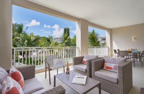 a patio with wicker chairs and tables on a balcony at Ki Residences with LOV in Pereybere