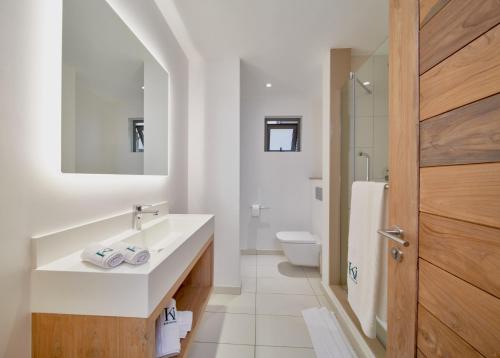 a white bathroom with a sink and a toilet at Ki Residences with LOV in Pereybere