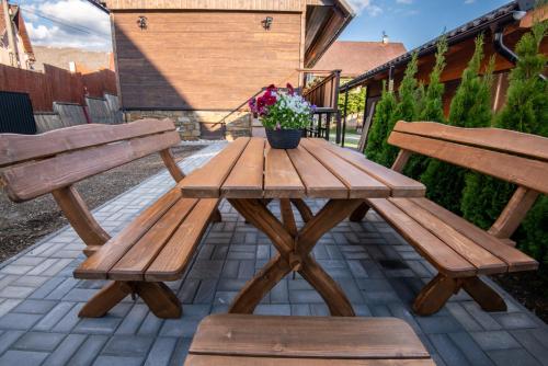 a wooden picnic table with two benches and a potted plant at Drevenica Irenka in Zuberec