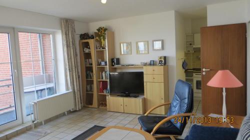 ein Wohnzimmer mit einem TV, einem Tisch und Stühlen in der Unterkunft Strandresidenz Sierksdorf Nr 01 in Sierksdorf