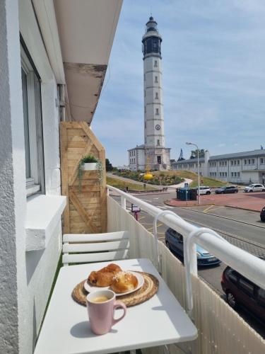 une assiette de nourriture et une tasse de café sur un balcon avec un phare dans l'établissement chez Sandy, à Calais