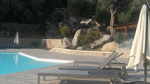 une piscine avec une chaise et des parasols à côté d'une piscine dans l'établissement Domaine d'Arca Corse du Sud - Piscine - T2 - 4 personnes 