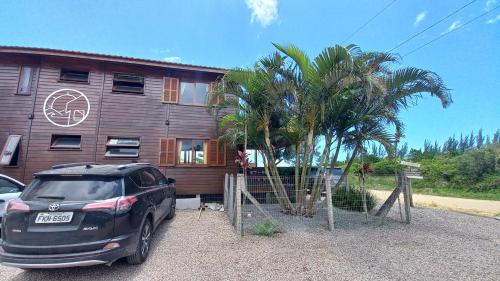 a car parked in front of a house with a palm tree at La Tatuira, Cabana Amarela in Pinheira