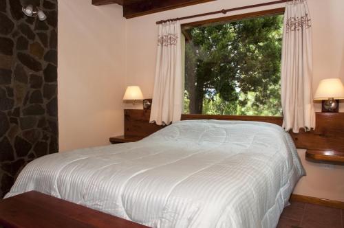 a bedroom with a bed and a large window at KaiKen Lauquen in Trevelin