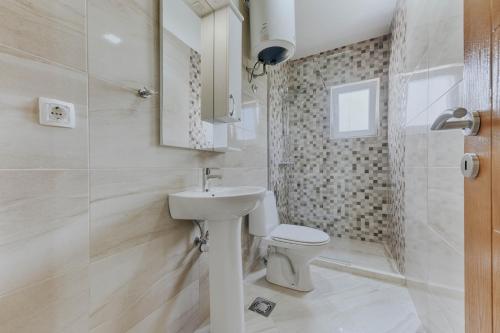 a white bathroom with a toilet and a sink at Sea Garden Apartments in Dobra Voda