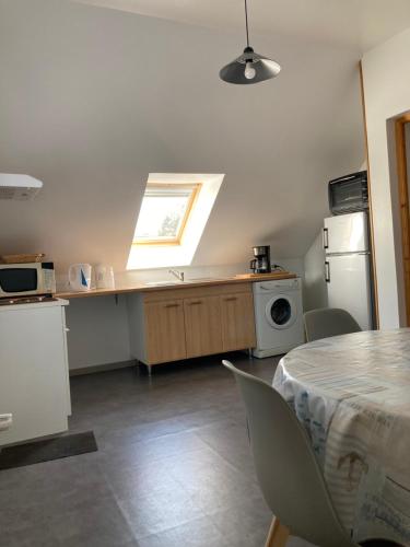 a kitchen with a table and a refrigerator and a window at La Garenne in Camiers
