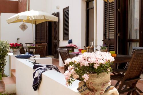 a patio with tables and chairs with pink flowers at Residence Scirocco e Tramontana in Favignana