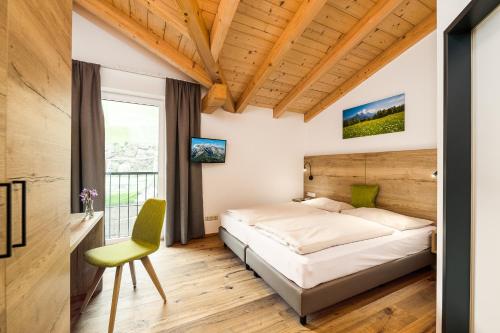a bedroom with a bed and a green chair at Apartmenthotel Sonnenhof in Maria Alm am Steinernen Meer