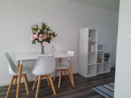 Light Blue Apartment في أفيرو: طاولة طعام مع كراسي و إناء من الزهور