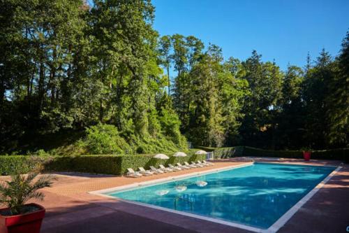 a swimming pool with chairs and umbrellas in a yard at Mobil-Home 6 pers sur une grande parcelle, proche Paris camping 3 étoiles in Mirgaudon