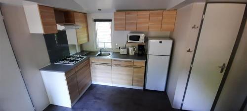 a small kitchen with a white refrigerator and a sink at Mobil-Home 6 pers sur une grande parcelle, proche Paris camping 3 étoiles in Mirgaudon