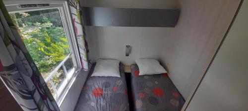 two beds in a small room with a window at Mobil-Home 6 pers sur une grande parcelle, proche Paris camping 3 étoiles in Mirgaudon