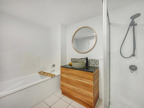 a bathroom with a tub and a sink and a mirror at Seaside Stays Marcoola Beach Apartment 1 Bedroom in Marcoola