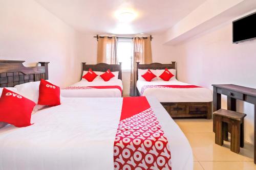 a bedroom with two beds with red and white pillows at OYO Hotel Punta Guadalupe, San Cristóbal de las Casas in San Cristóbal de Las Casas