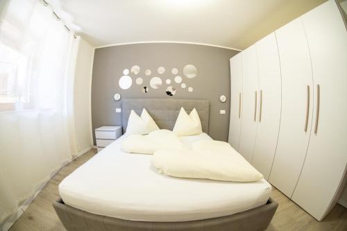 1 dormitorio con 1 cama blanca grande y armarios blancos en Flow Apartments Trogmann, en Merano