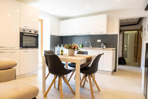 Una cocina con una mesa de madera y sillas negras. en Flow Apartments Trogmann, en Merano