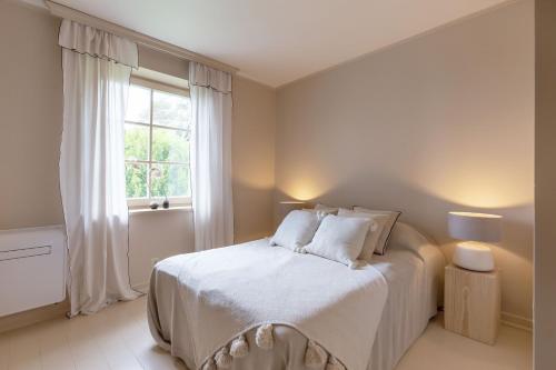 a white bedroom with a bed and a window at Nidos Banga in Nida