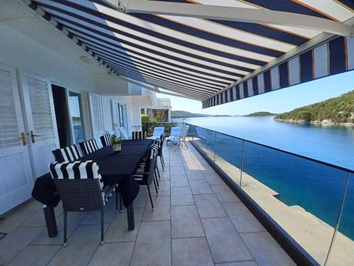 eine Terrasse mit einem Tisch und Stühlen sowie Blick auf das Wasser in der Unterkunft Vacation Home Vidučić in Dragove