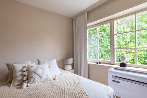 a white bedroom with a bed and windows at Nidos Banga in Nida
