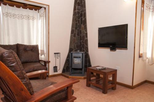 sala de estar con sofá, TV y silla en KaiKen Lauquen en Trevelín