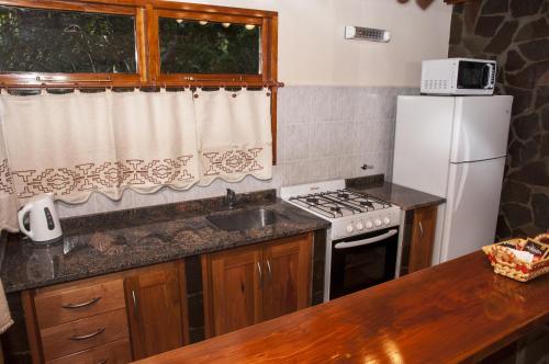 a kitchen with a sink and a stove and a refrigerator at KaiKen Lauquen in Trevelin