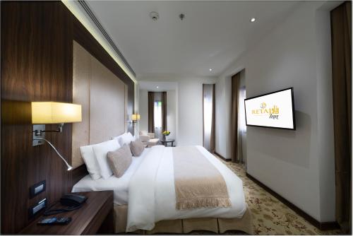 a hotel room with a large bed and a television at Retaj Inn Al Wakrah in Al Wakrah
