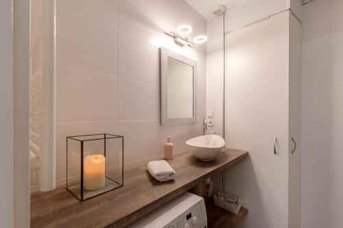 La salle de bains est pourvue d'un lavabo et d'une bougie sur un comptoir. dans l'établissement Travel Homes - The Ancienne Poste, Petite Venise, à Colmar