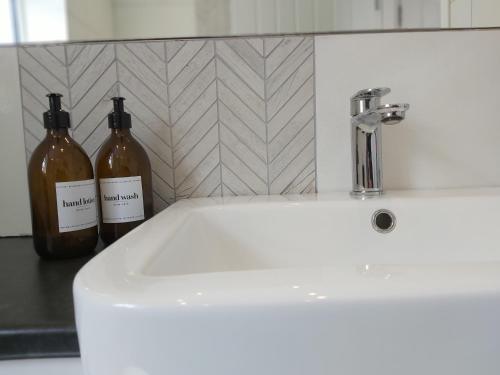 two bottles of wine sitting on top of a sink at Modern 4 Bedroom House with Parking in Wyken