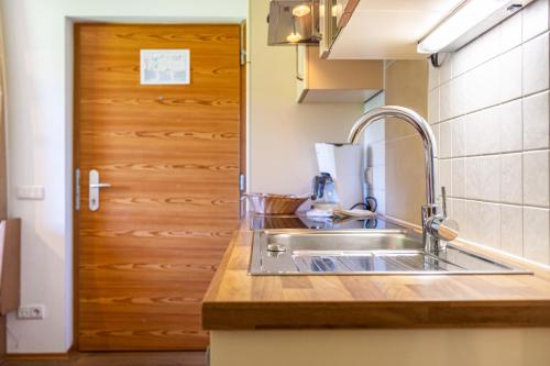 a kitchen with a sink and a wooden door at Ferienparadies Sabina Piz in Alpe di Siusi