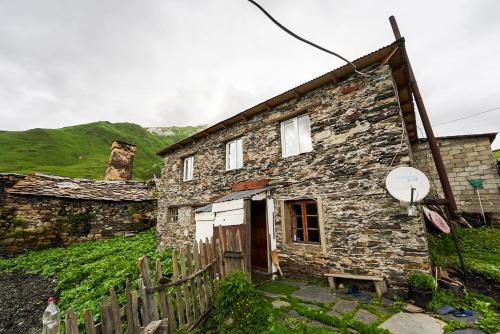an old stone house with a fence in front of it at Guesthouse Nora in Ushguli