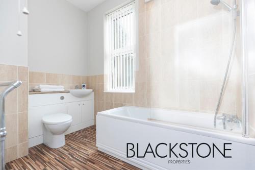 a bathroom with a white tub and a toilet at Cheerful one-bedroom house, with on-street parking by BPNE in Darlington